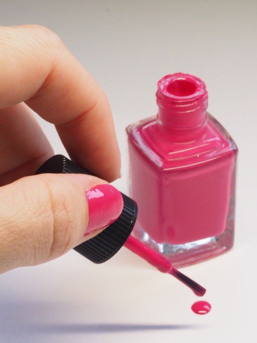 Hands holding a bottle of pink nail polish
